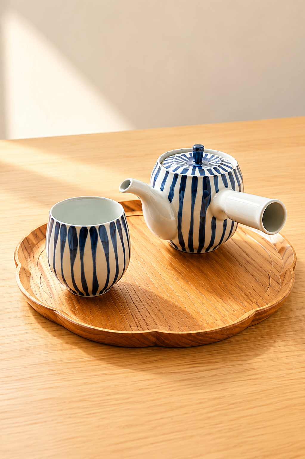 Hand-painted Tokusa kyusu teapot pouring green tea into matching Japanese yunomi cups on a wooden tray