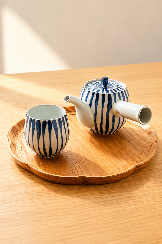 Hand-painted Tokusa kyusu teapot pouring green tea into matching Japanese yunomi cups on a wooden tray